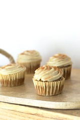 Chai-infused cupcakes with vanilla frosting on a wooden display tray