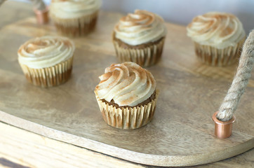 Chai-infused cupcakes with vanilla frosting on a wooden display tray