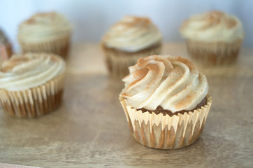Chai-infused cupcakes with vanilla frosting on a wooden display tray