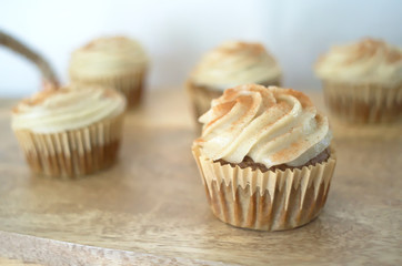 Chai-infused cupcakes with vanilla frosting on a wooden display tray