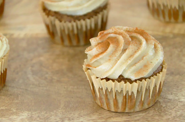 Chai-infused cupcakes with vanilla frosting on a wooden display tray