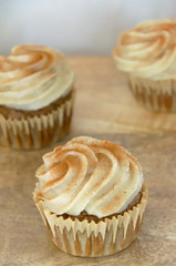 Chai-infused cupcakes with vanilla frosting on a wooden display tray