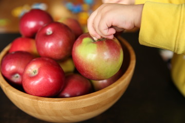 apple in the hand of a child from a wooden vase with apples