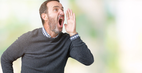 Handsome middle age senior man wearing a sweater over isolated background shouting and screaming loud to side with hand on mouth. Communication concept.