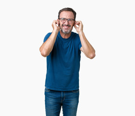 Fototapeta premium Handsome middle age hoary senior man wearin glasses over isolated background covering ears with fingers with annoyed expression for the noise of loud music. Deaf concept.