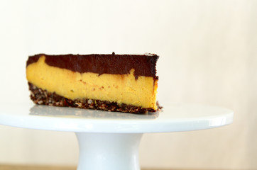 A slice of vegan cheesecake covered in chocolate