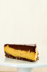 A slice of vegan cheesecake covered in chocolate