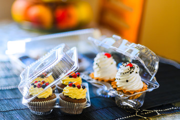 Cakes in a plastic disposable container on a colored background