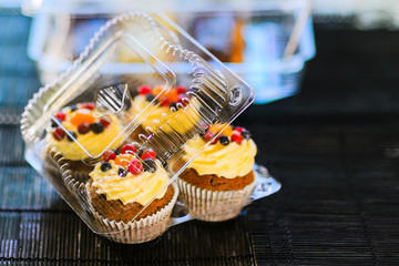 Cakes in a plastic disposable container on a colored background