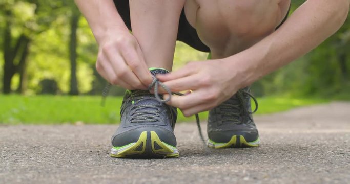 Female runner tying a loose shoe lace in a park.