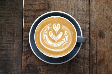 a cup of latte art coffee on wooden background