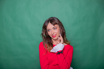 body language and emotions. Studio shot of young fair-haired woman on green background. Girl looking away holding hand on chin, building plans, thinking about something. pensive face expression.Copy
