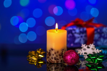Obraz na płótnie Canvas burning candles and Christmas decorations on table with reflection on bokeh background with blurred background