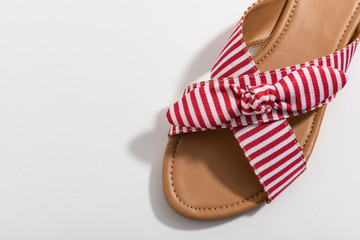 Sandalia de mujer con lineas rojas y blancas con un moño. Moda. En fondo blanco