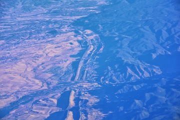 Aerial view of topographical Rocky Mountain landscapes on flight over Colorado and Utah during autumn. Grand sweeping views of rivers, mountain and landscape patterns. Top view, Rockies and Wasatch