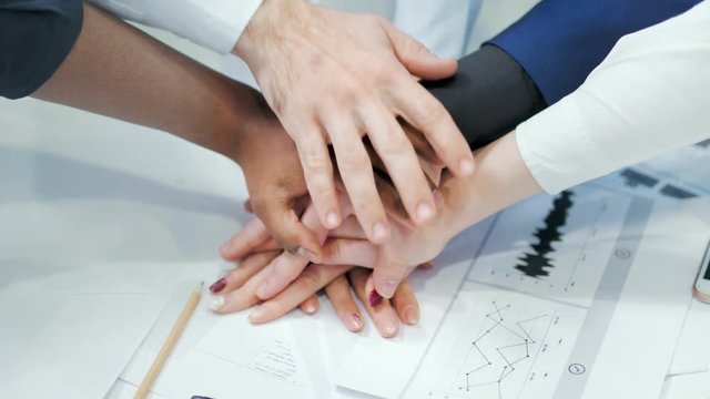 Close-up group multinational business people putting their hands on each other during team meeting