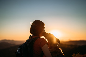 dog kissing girl at sunset