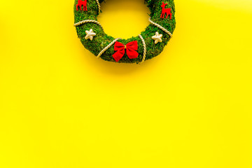 Christmas wreath traditional, classic type. Wreath made of spruce branches and red ribbons on yellow background top view space for text