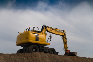 Bagger auf Erdhügel von schräg hinten