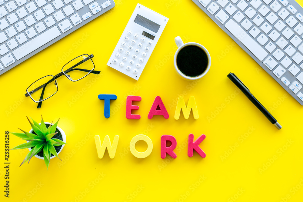 Poster teamwork in office. text team work lined with colored letters on yellow office desk with computer ke