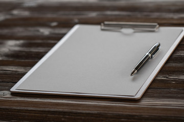 Clipboard with white sheet on wood background. Top view.Vintage style.