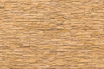 Rock stone brick tile wall aged texture detailed pattern background in yellow brown color