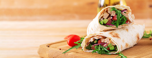 Tortillas wraps with chicken and vegetables on  wooden background. Chicken burrito. Banner. Healthy food. - obrazy, fototapety, plakaty