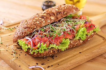 Salmon sandwich - smorrebrod with cheese cream and microgreen on wooden table.