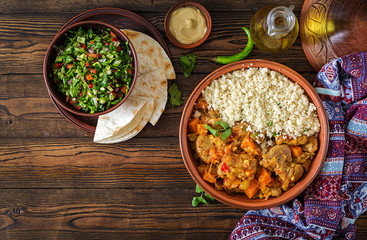 Traditional tajine dishes, couscous  and fresh salad  on rustic wooden table. Tagine lamb meat and...