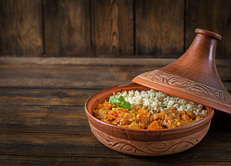 Traditional tajine dishes, couscous  and fresh salad  on rustic wooden table. Tagine lamb meat and...