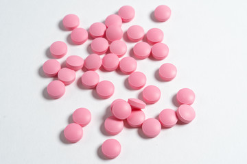 pink pills scattered on a white background.