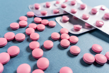 Obraz na płótnie Canvas Bright pink pills on dark blue coloured background