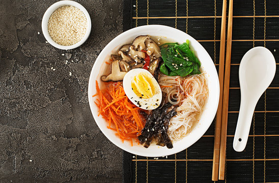 Diet vegetarian bowl of noodle soup of shiitake mushrooms, carrot and boiled eggs.  Japanese food. Top view. Flat lay