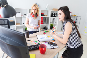 Two girls work in the office. The girl is holding a model of a man.