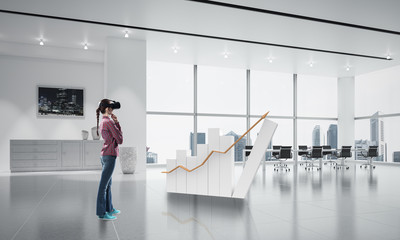 Girl in office interior in virtual reality mask using innovative