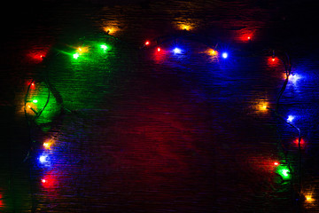 multicolored Christmas lights on a wooden background