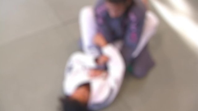 Two Girls Training in Brazilian Jiu Jitsu on Mat Floor - Out of Focus
