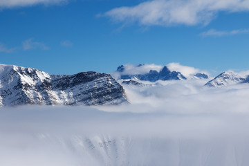 Fototapeta na wymiar Snowy sunlight mountains in haze and blue sky at nice sun day
