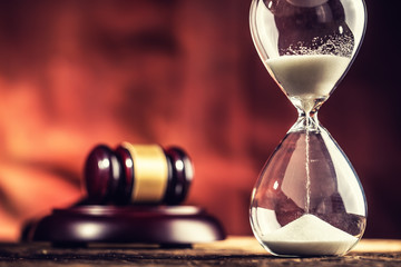 Modern hourglass in running time and justice hammer on wooden table