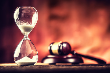 Modern hourglass in running time and justice hammer on wooden table