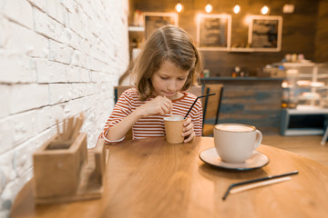 Little girl in a cafe with a milk drink