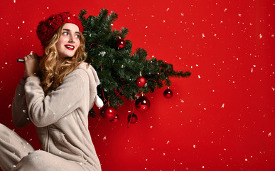 Young woman hold winter christmas fir tree decoration in knitted hat under snow. New year concept