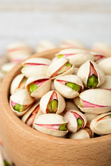 pistachio nuts with shell in the wooden bowl, on the wooden board