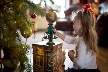 girl decorates Christmas tree at home