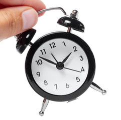 Female hand holding alarm clock on white background