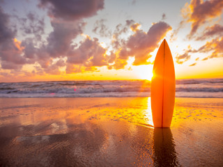 surfplank op het strand in de kust bij zonsondergang met prachtig licht