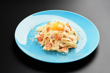 Traditional Italian pasta dish, spaghetti carbonara yolk, parmesan cheese, bacon plate black background menu