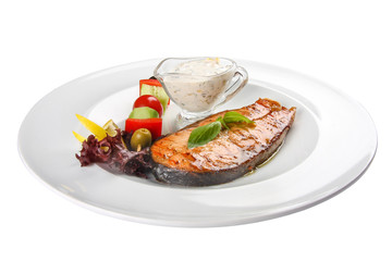 Salmon steak with vegetables and sauce. On a white background