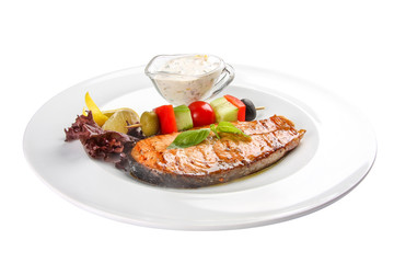 Salmon steak with vegetables and sauce. On a white background