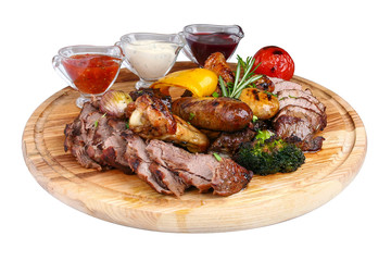 Assorted grilled meat with baked vegetables on a wooden board